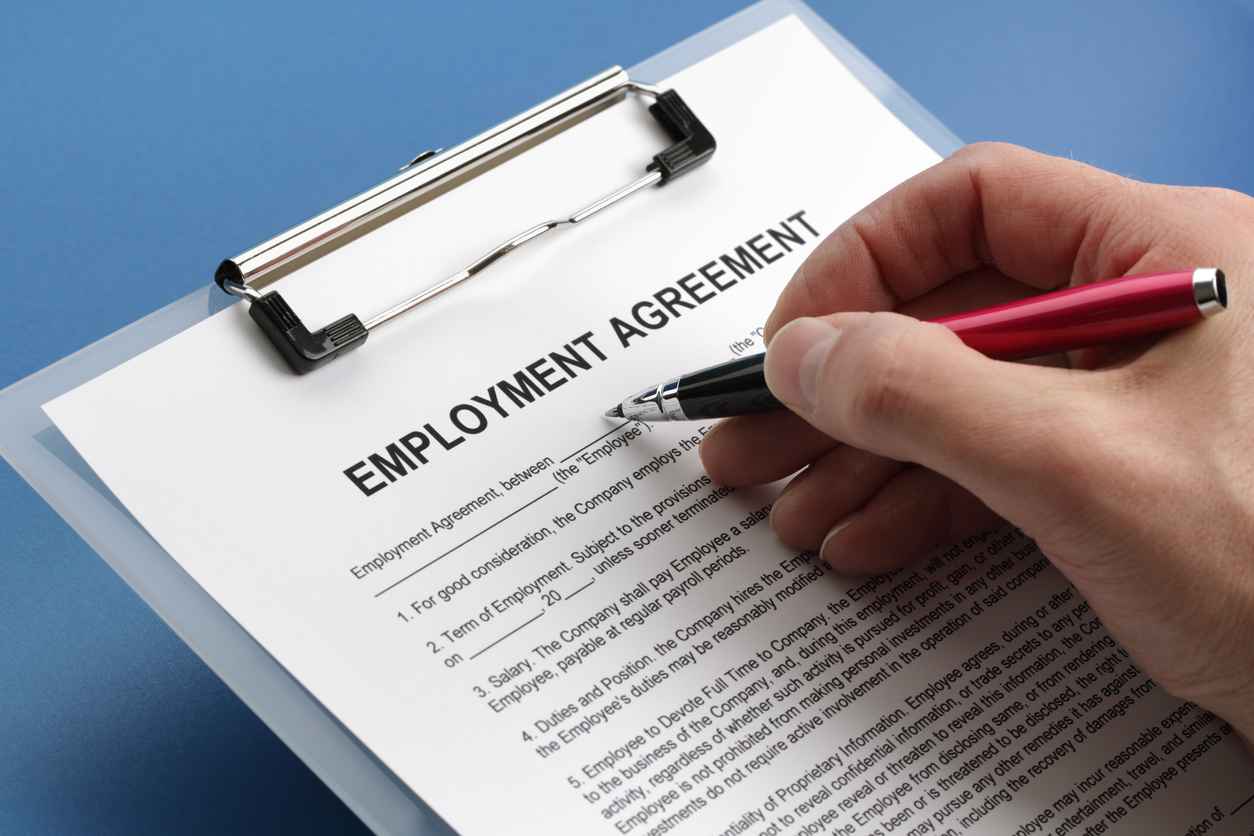Man filling out an employment agreement contract; The Importance of Clear and Effective Employment Contracts